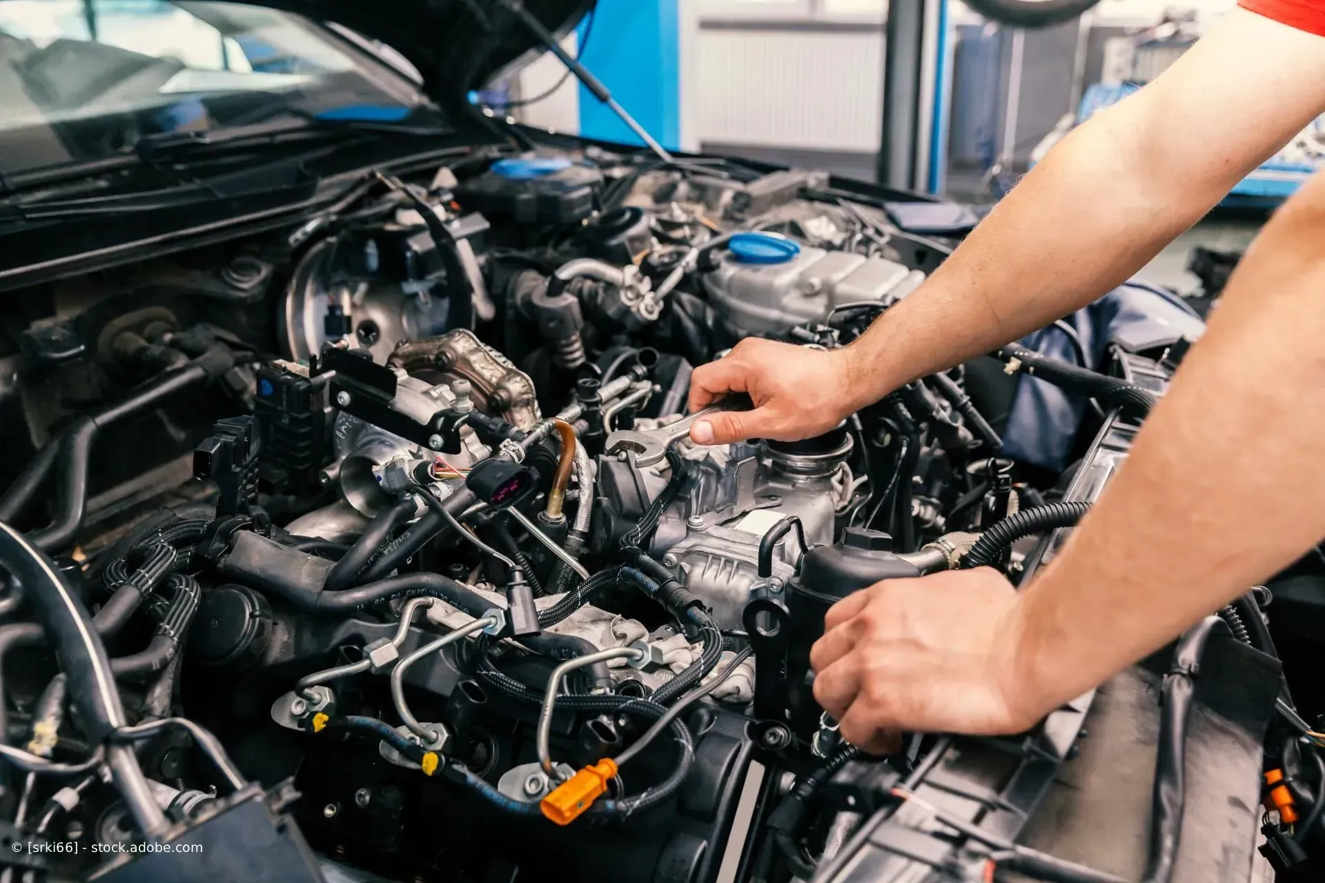 Ein Mechaniker arbeitet in einer Werkstatt an einem Automotor.