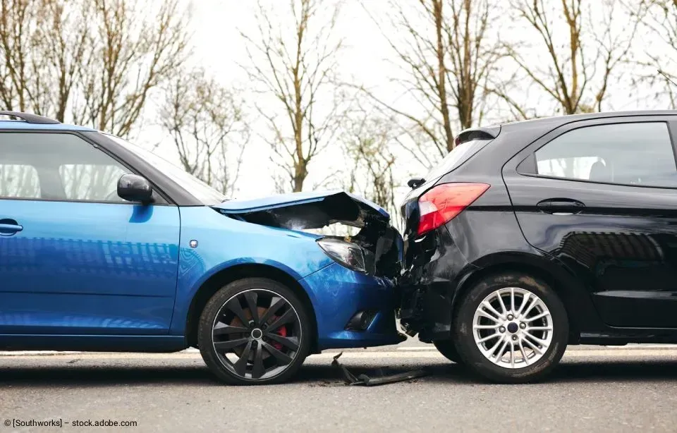 Blaues und schwarzes Auto kollidierten frontal, beide Fronten sichtbar beschädigt.