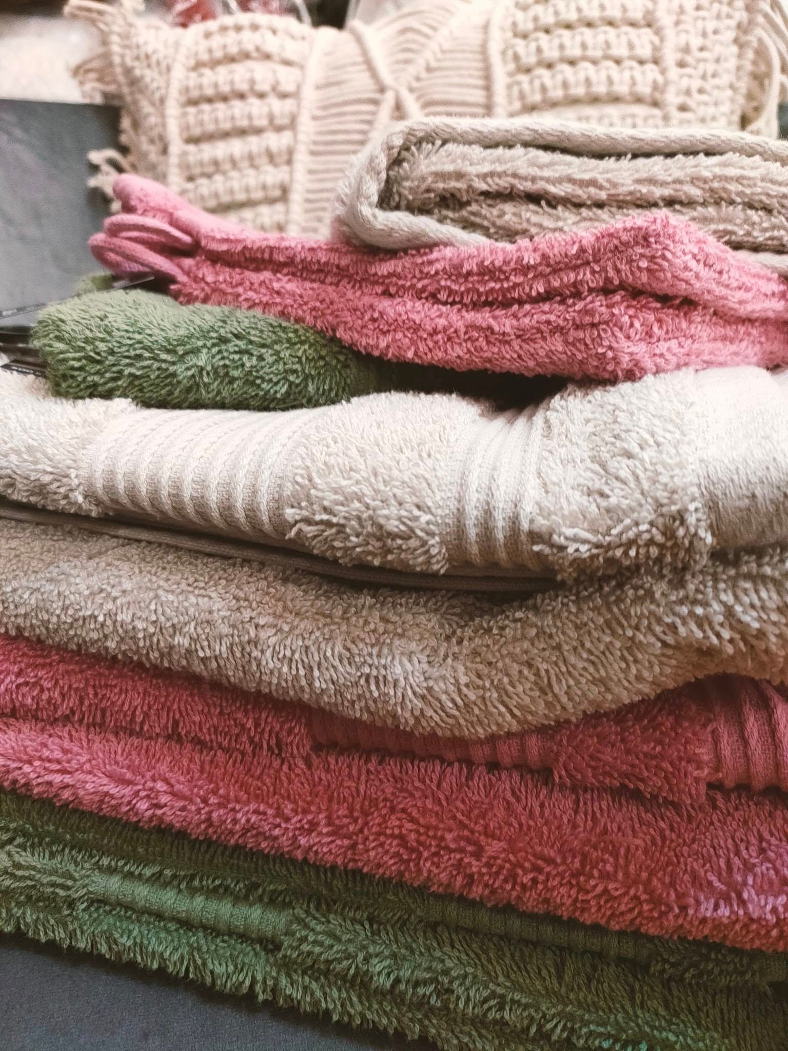 Des serviettes de bain de couleur blanche, rose et verte.