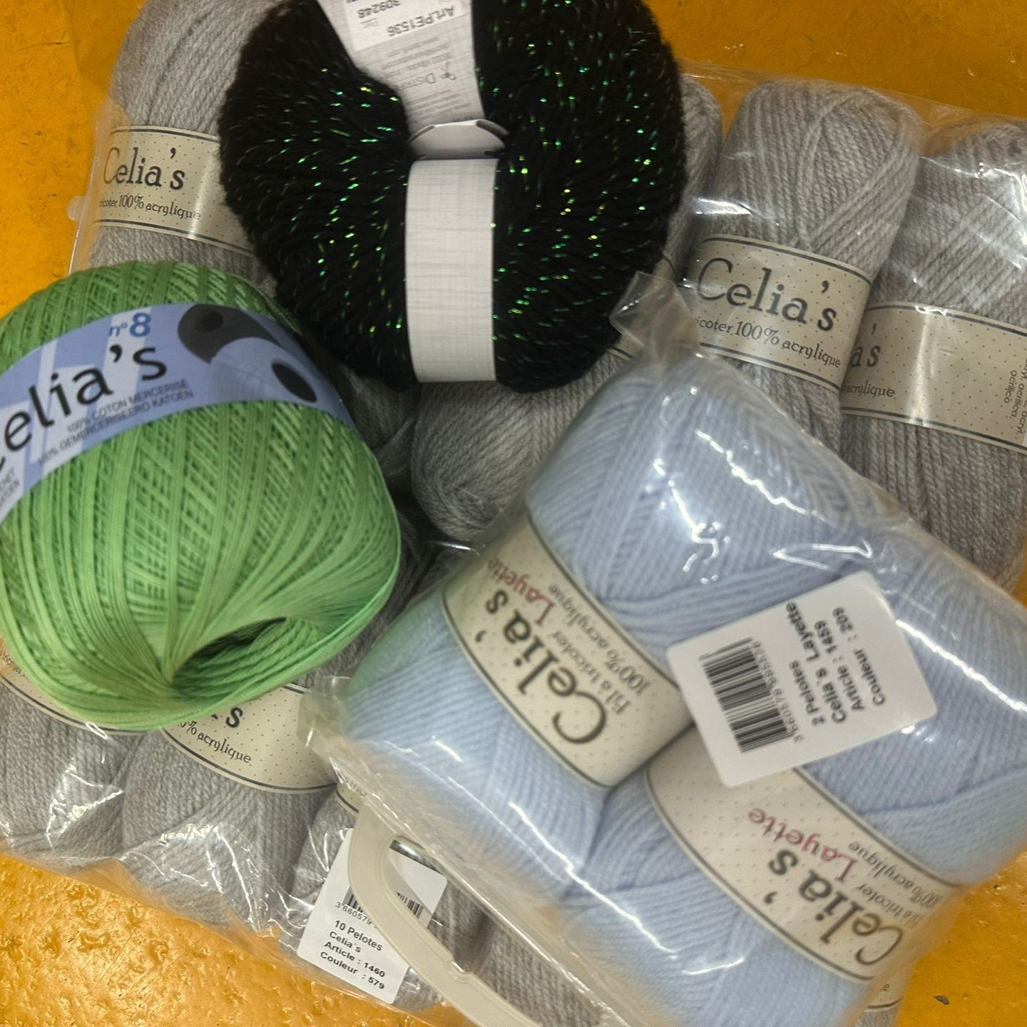 Des écheveaux de laine assortis, verts, noirs, blancs et bleu clair.