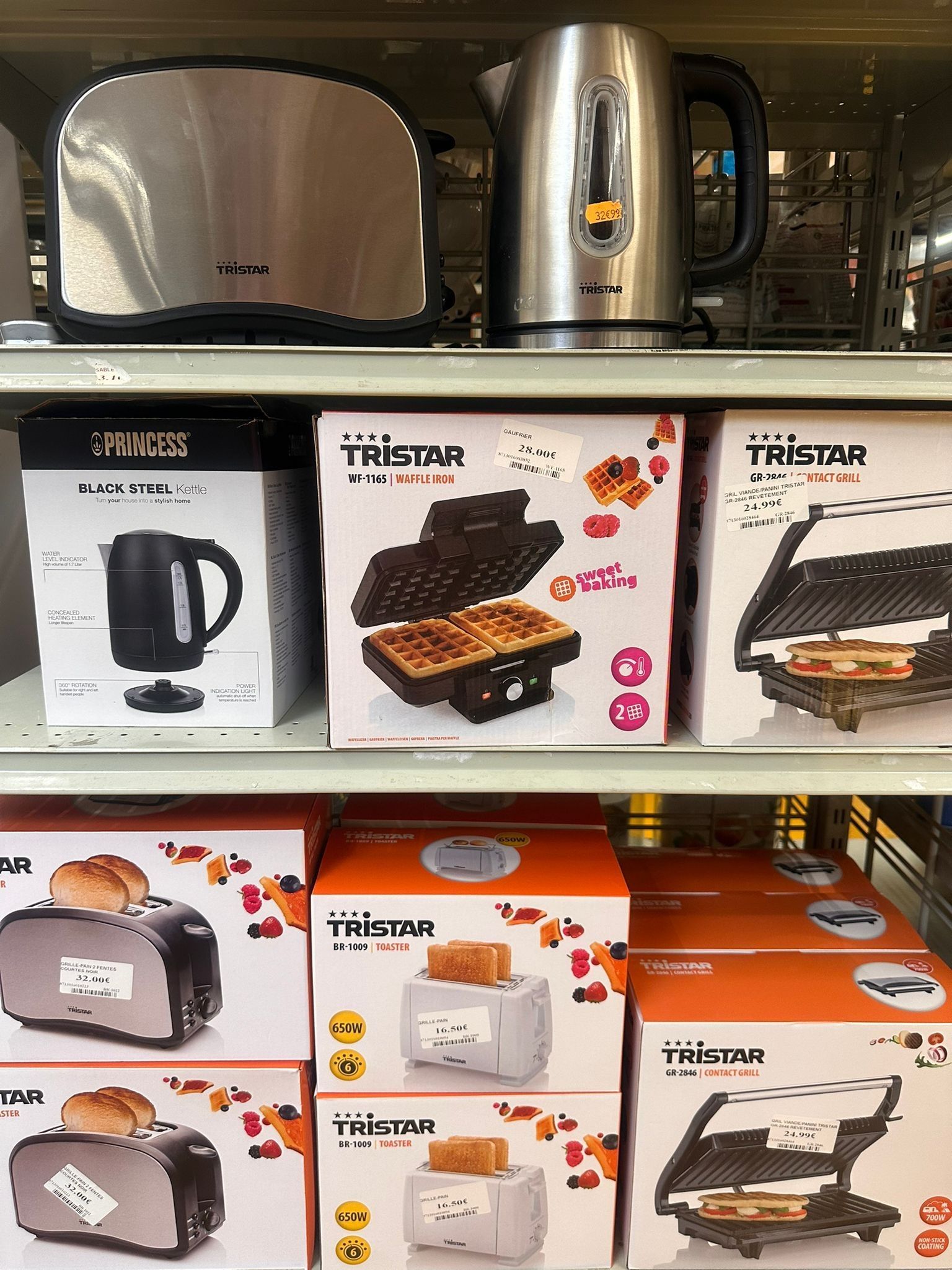 Des bouilloires, des gaufriers et des appareils à sandwichs sur des étagères de magasin.