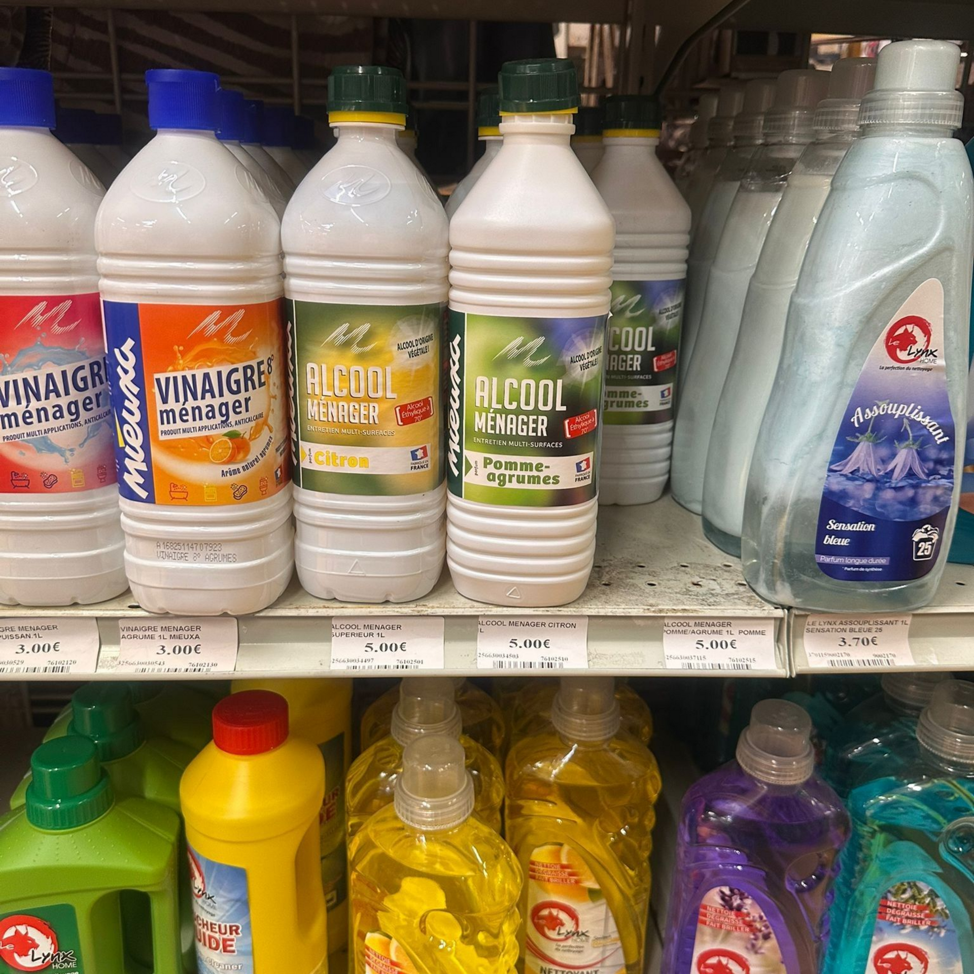 Vinaigres et bouteilles de produits nettoyants sur une étagère de magasin.