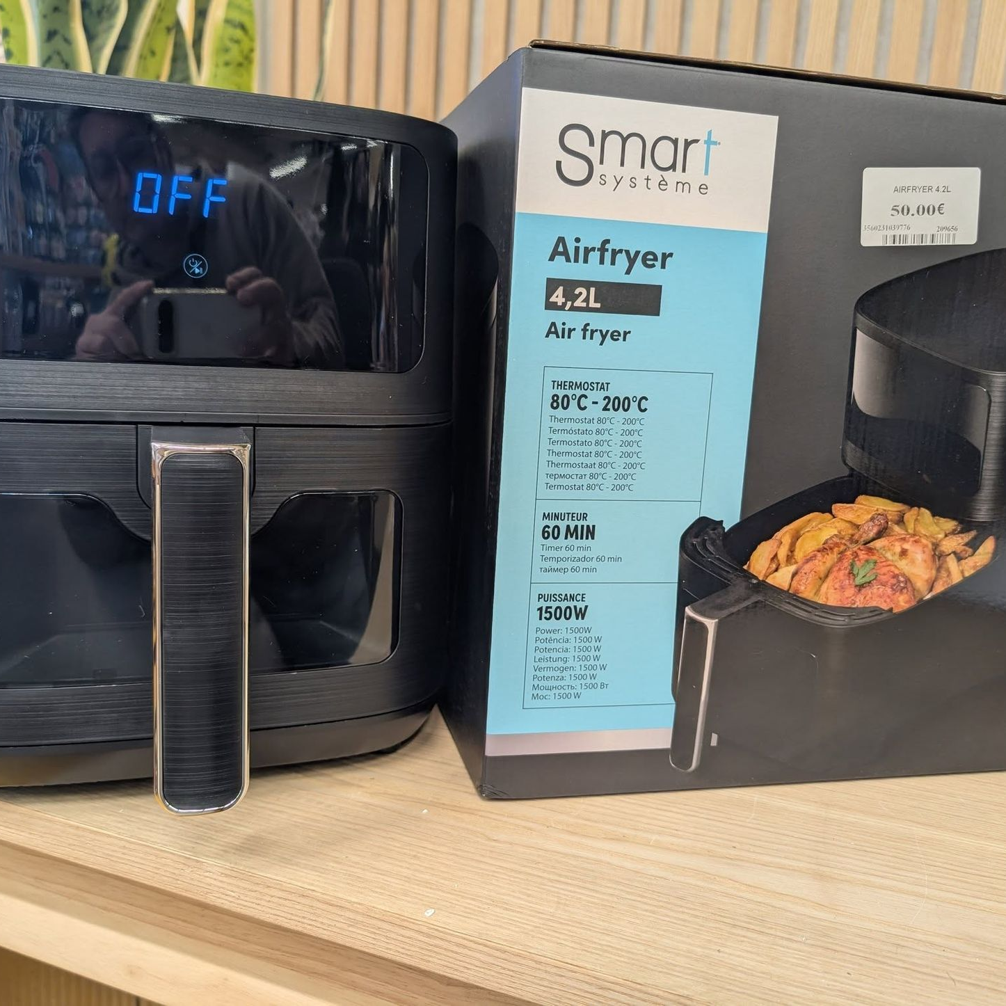 Airfryer noir posé à côté de sa boîte sur un comptoir en bois.