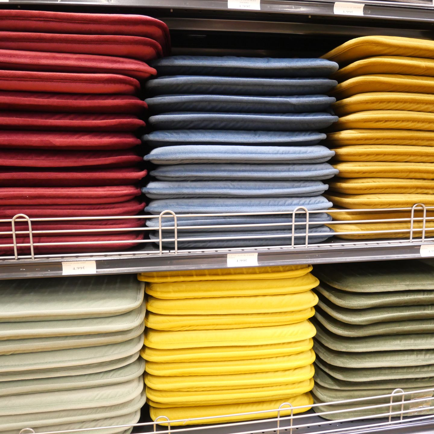Des étagères remplies de coussins rouges, bleus, jaunes et verts pour chaises.