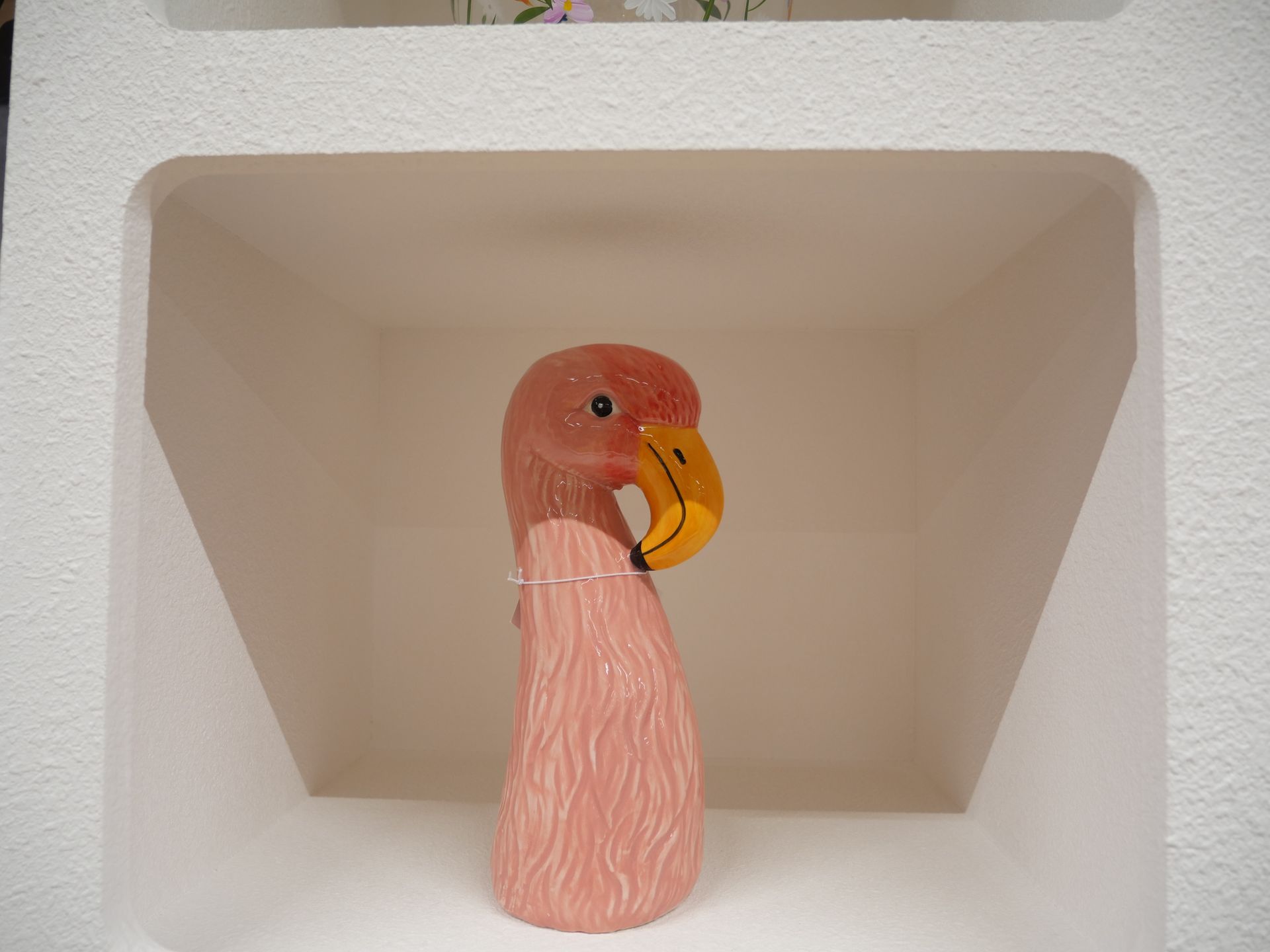 Figurine de flamant rose dans une niche blanche.