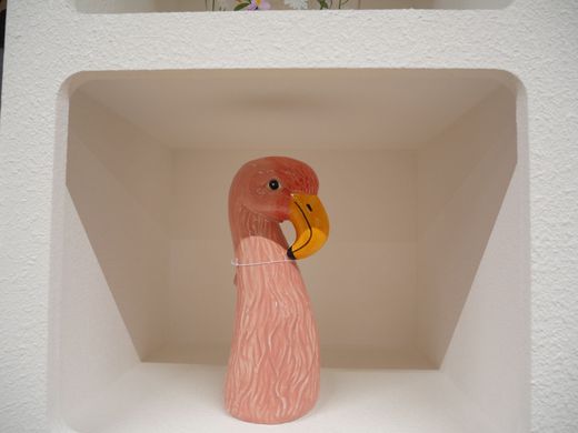 Figurine de flamant rose au bec jaune dans une niche murale blanche