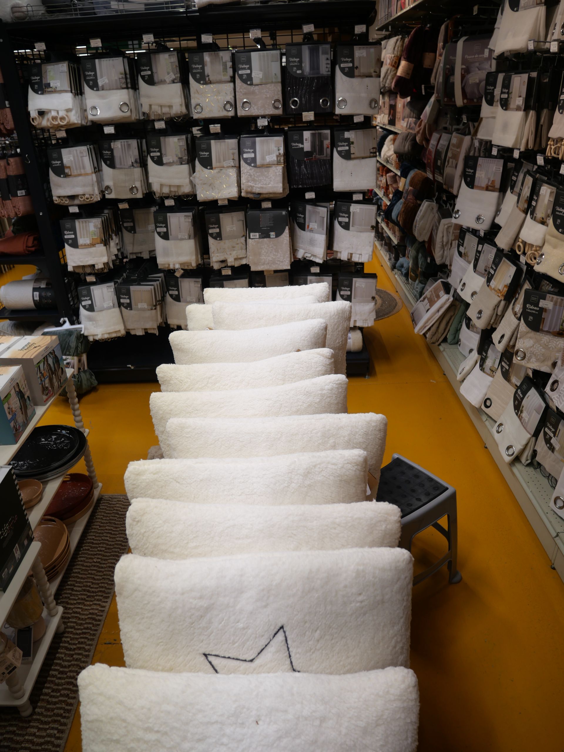Des rideaux de différentes couleurs en rayon et une rangée de coussins ou d'oreillers blancs au centre.