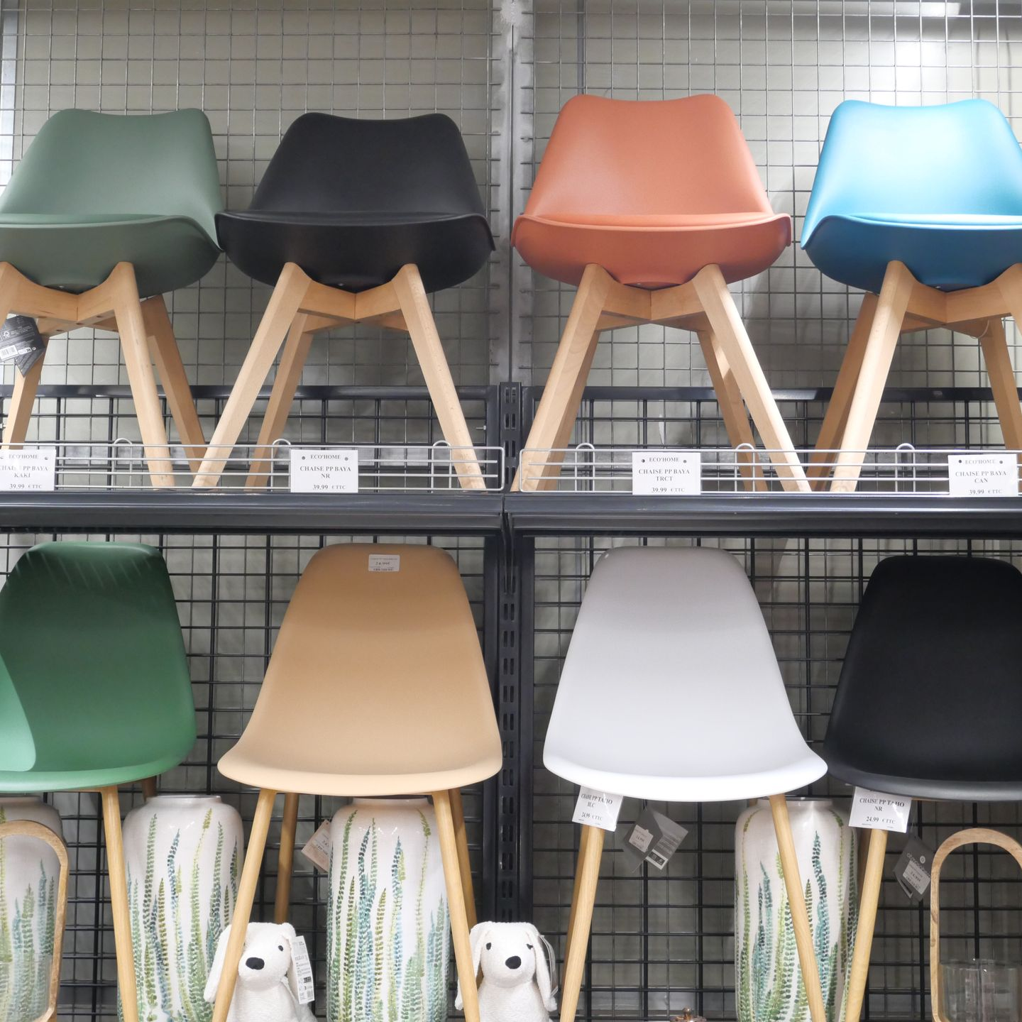 Des chaises colorées sont exposées sur des étagères de magasin.