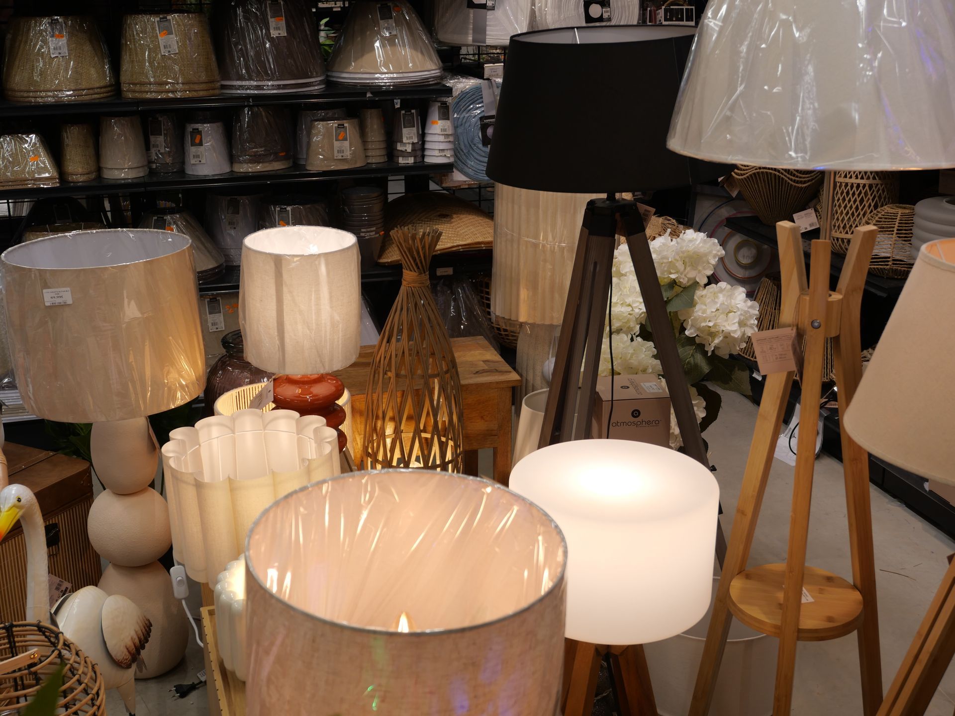 Un assortiment de lampes de table et d'abat-jour est exposé dans un magasin, comprenant des modèles blancs, beiges et en bois.