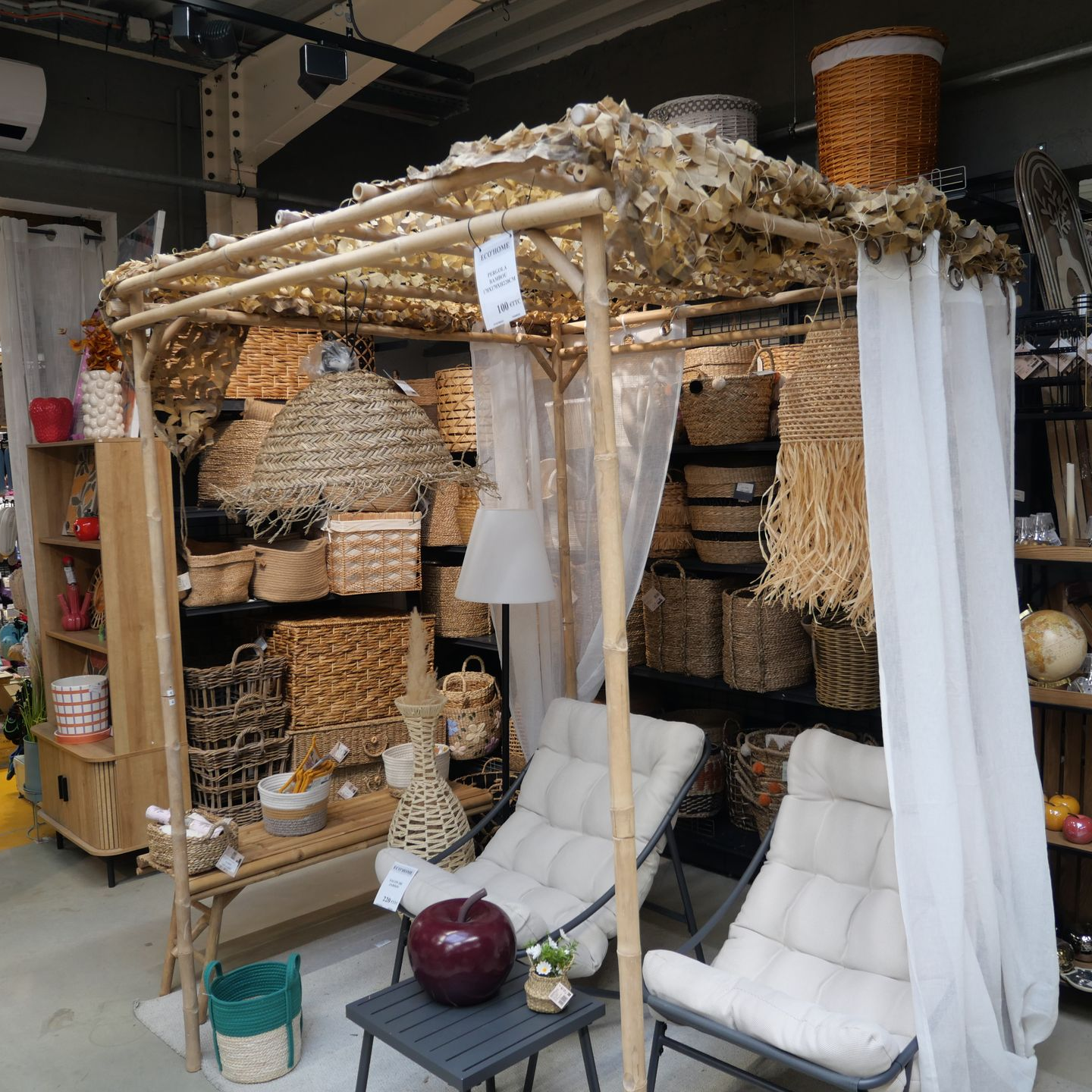 Des étagères remplies de paniers tressés et d'objets décoratifs sont présentées sous une petite pergola en bois.