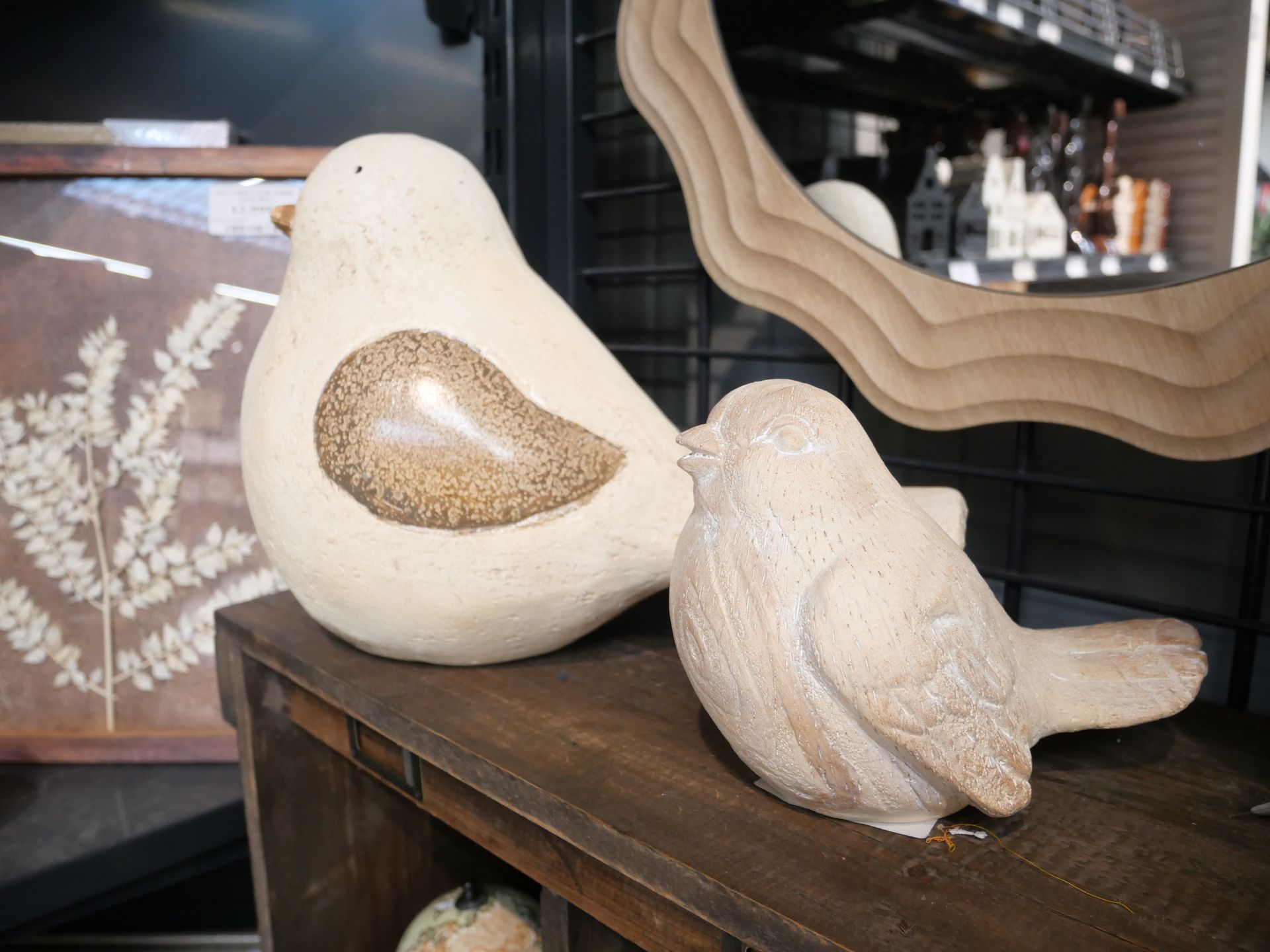 Deux figurines d'oiseaux décoratifs blancs sur un meuble en bois.