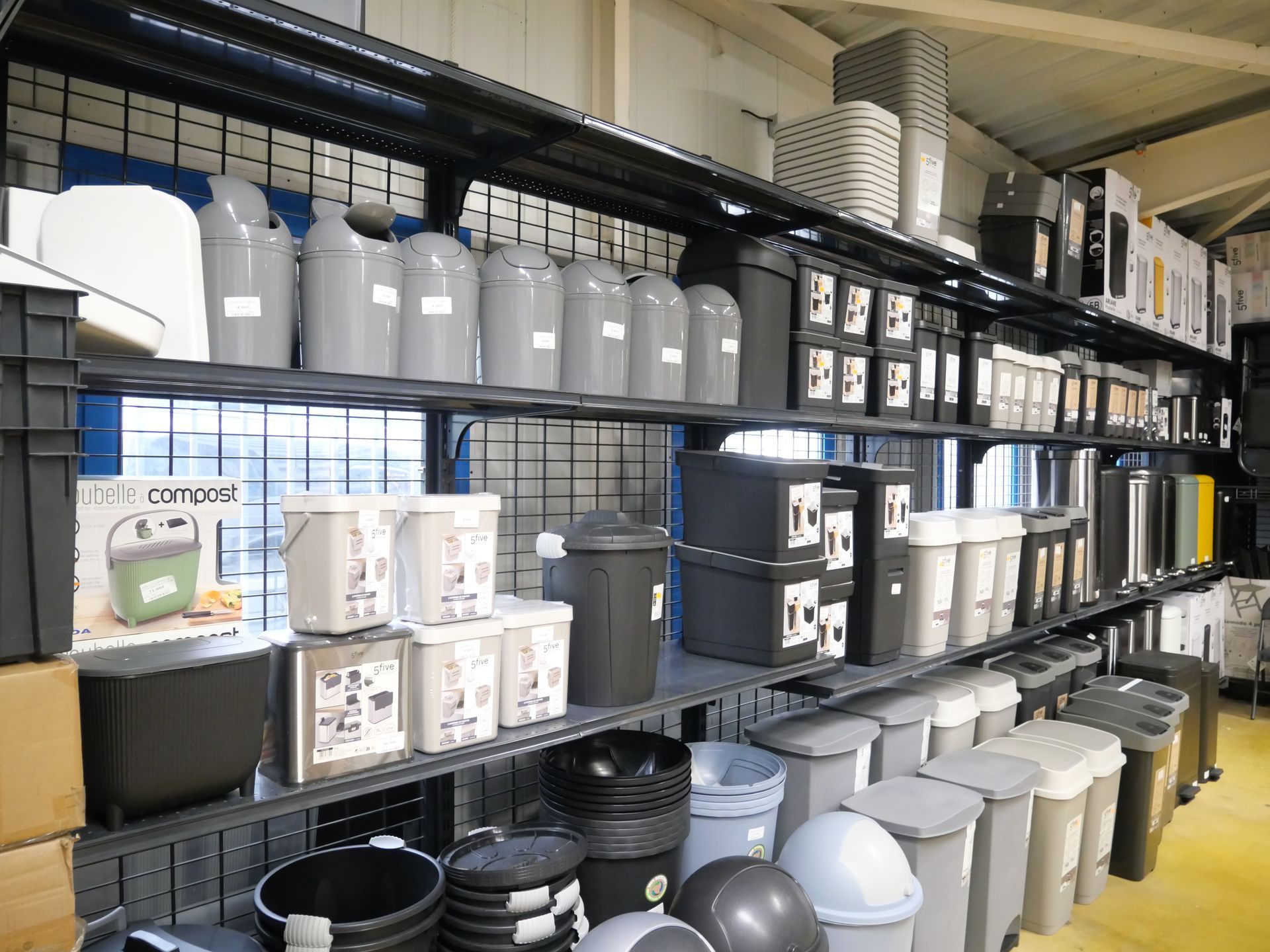 Des étagères remplies de boîtes de rangement et de poubelles.