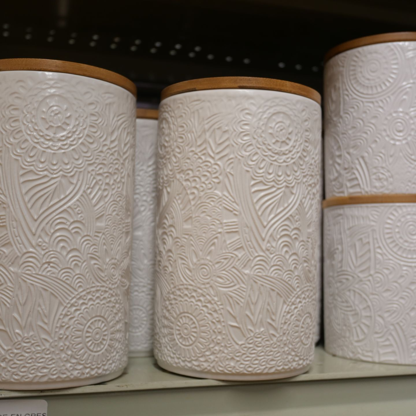 Trois boîtes de rangement cylindriques en relief avec couvercles en bois sur une étagère.