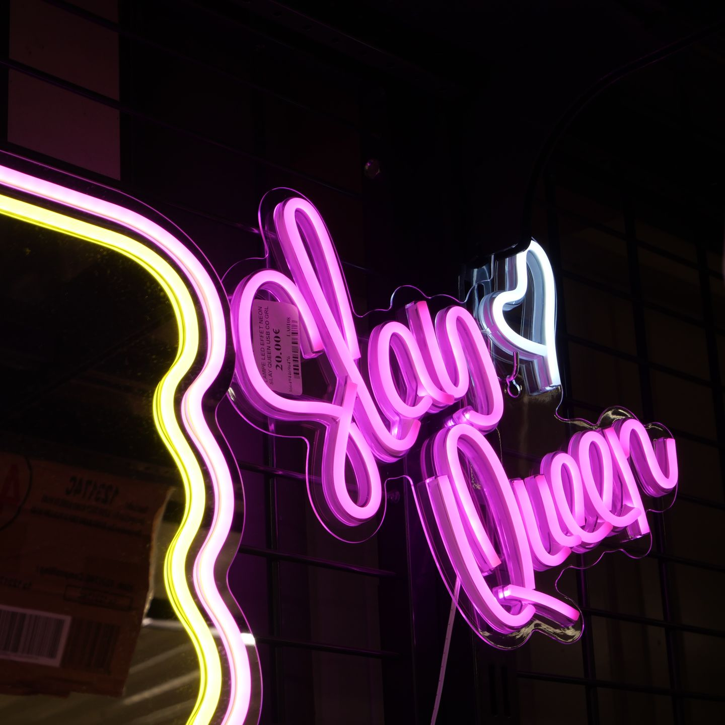 Enseigne lumineuse rose fluorescente sur un mur sombre.