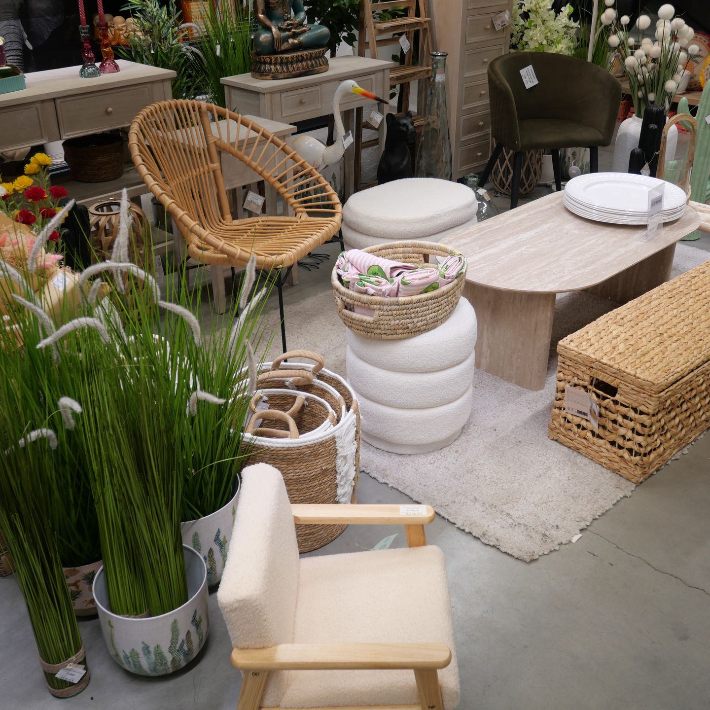 Mobilier d'extérieur avec chaises en osier, tables, tabourets, paniers et fausses plantes dans des pots.