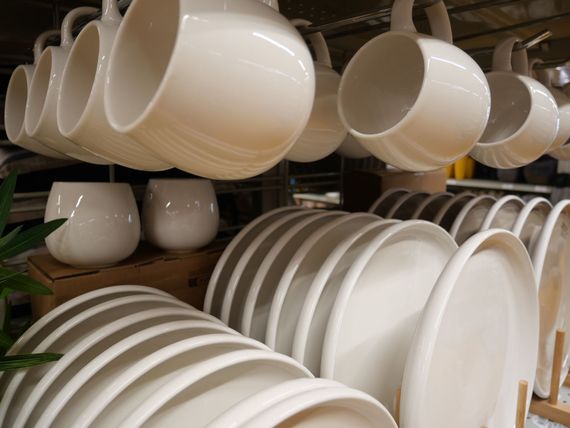 Assiettes et tasses blanches empilées, séchant sur les étagères de la cuisine