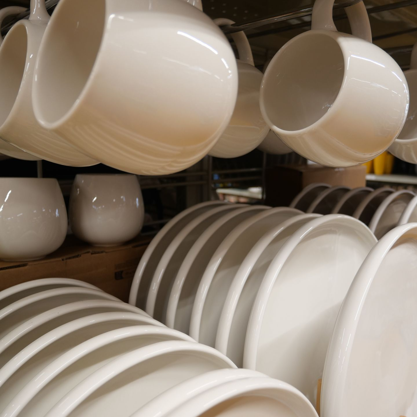 Des piles d'assiettes et de tasses sur des étagères dans un magasin.