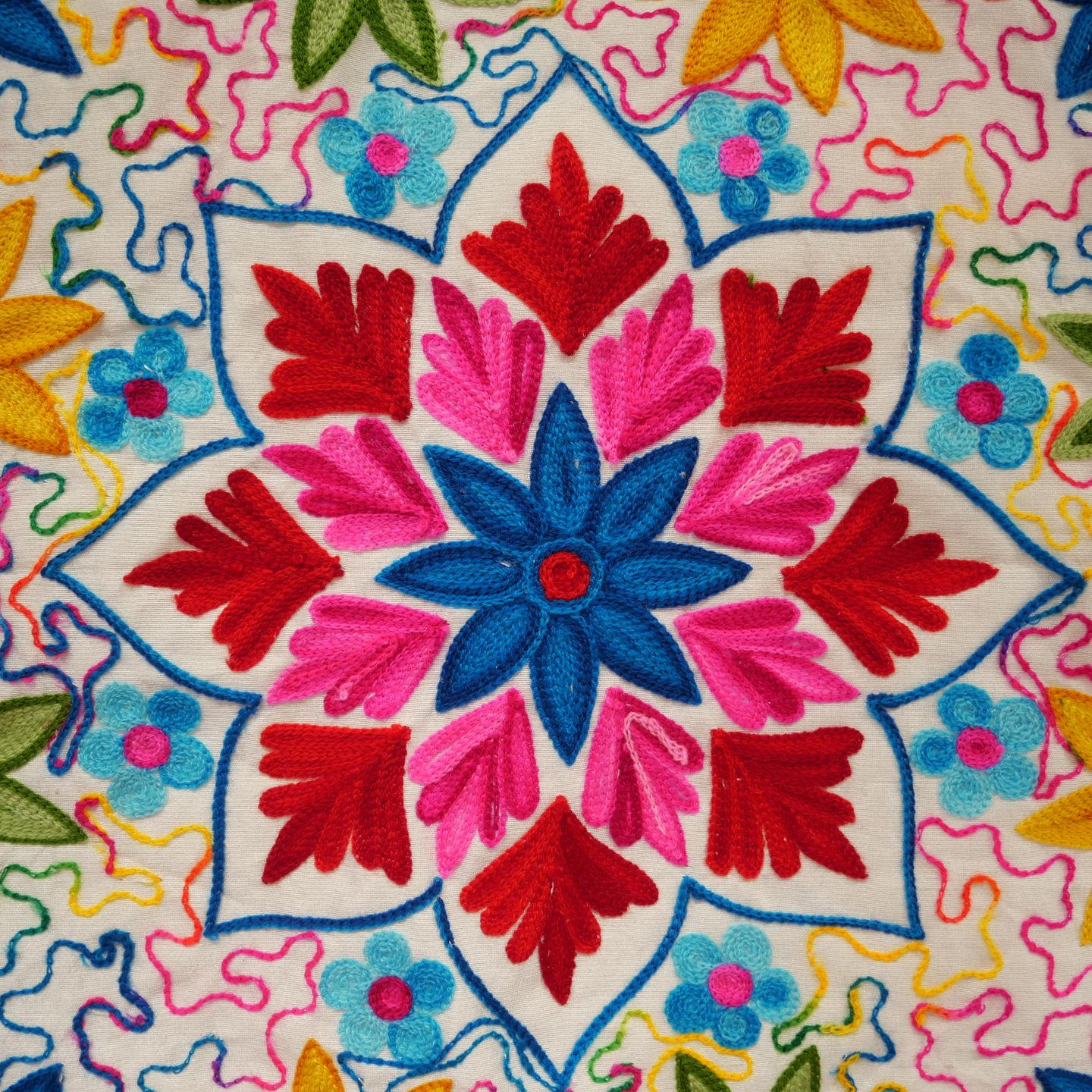 Mandala floral brodé et coloré avec des accents rouges, bleus, roses et jaunes sur fond blanc