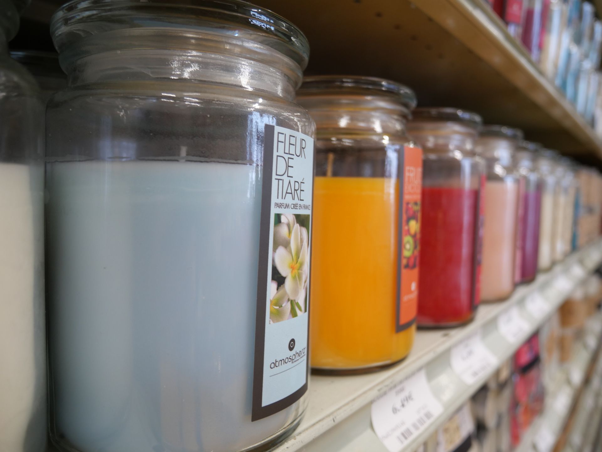 Bougies de couleur blanche, orange, rouge et rose dans des pots transparents.