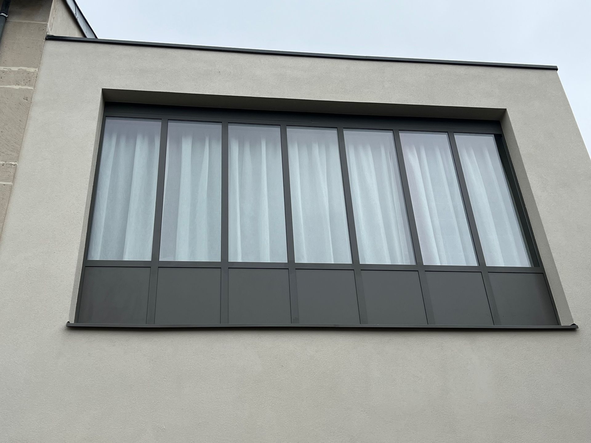 Portes-fenêtres à cadre noir et à plusieurs vitres, recouvertes de plastique, probablement en cours de rénovation.