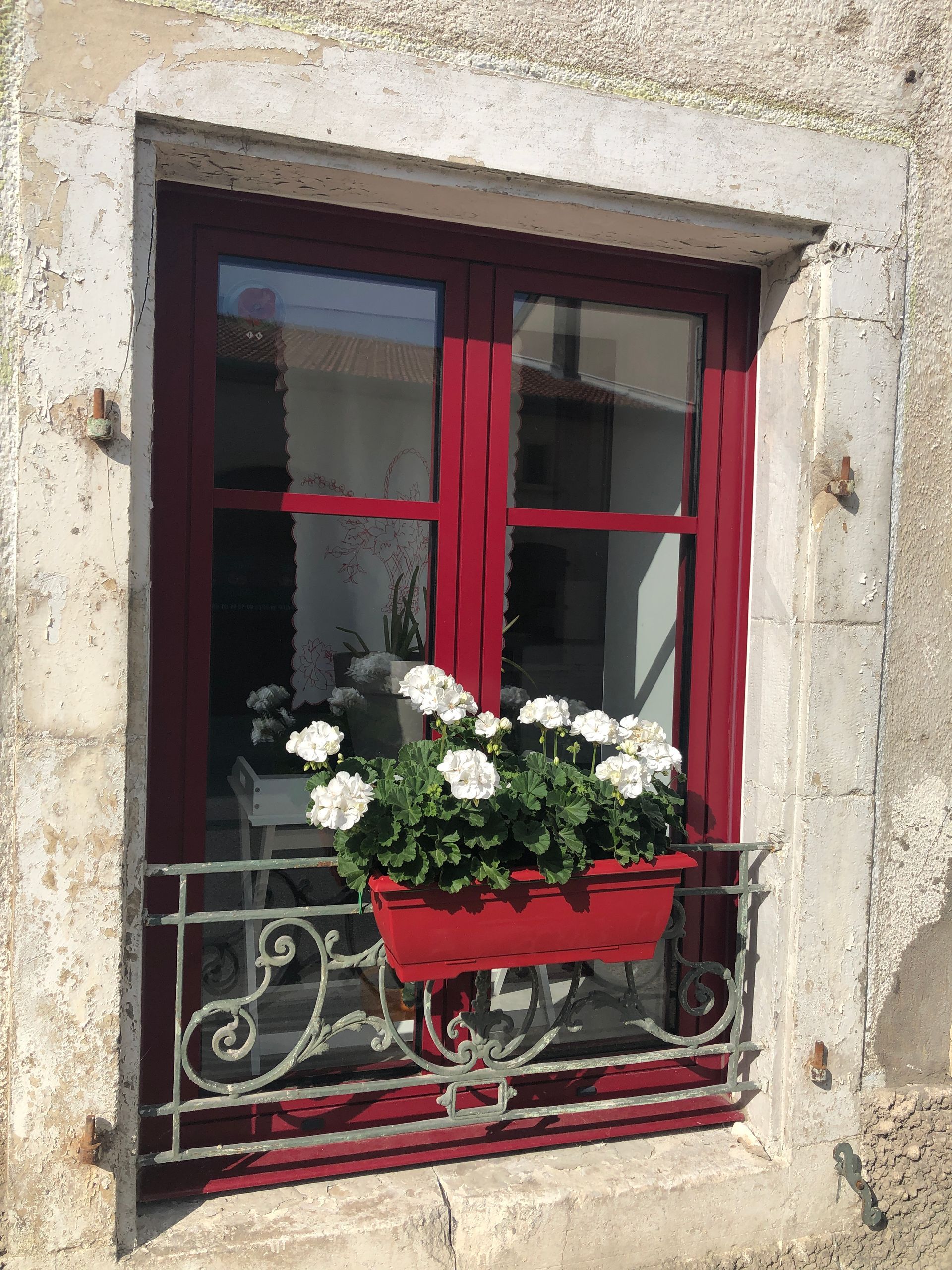 Grande fenêtre dans un immeuble en construction, donnant sur les toits. Cadre gris foncé et verre clair.
