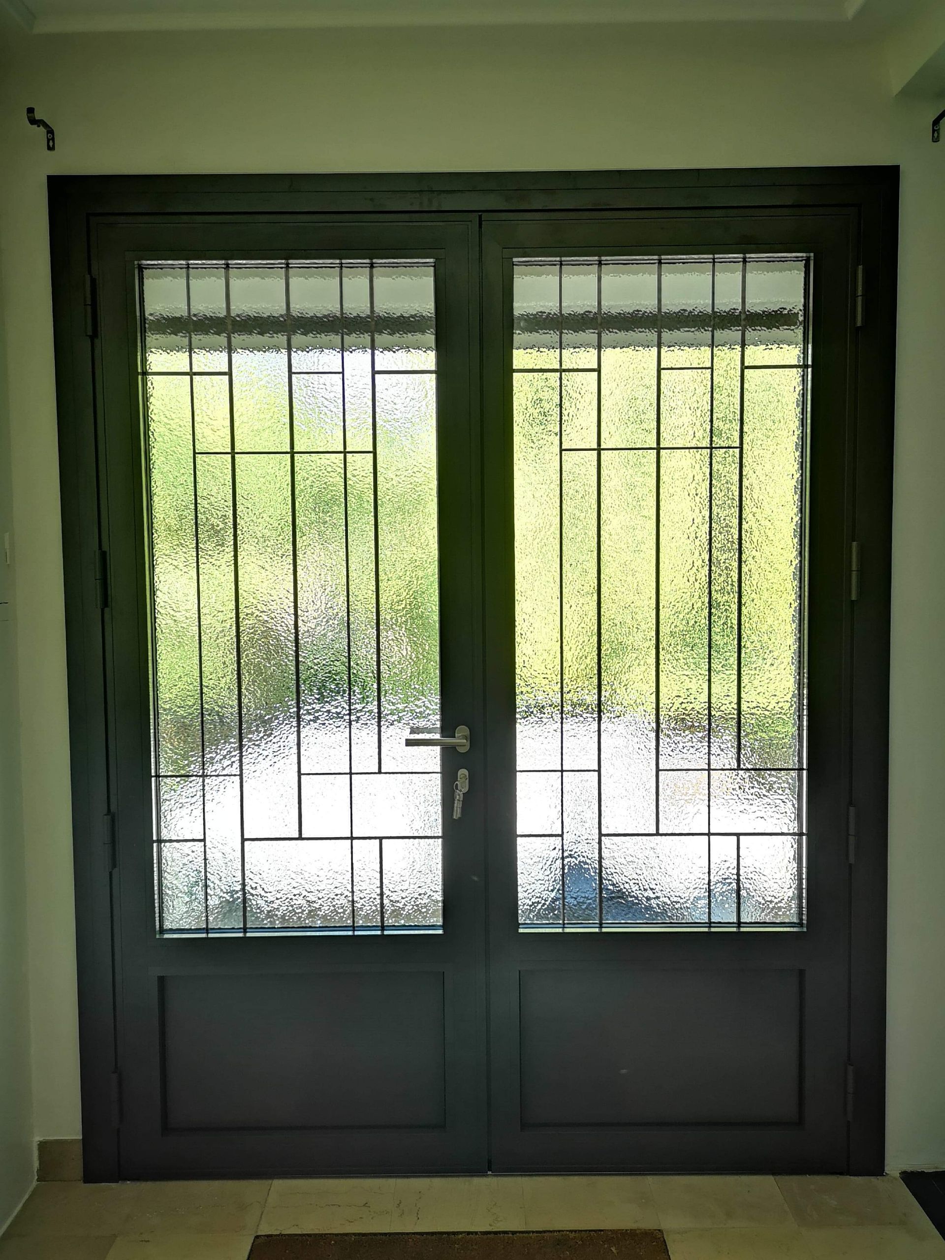 Porte à cadre blanc avec panneaux de verre et vue sur le jardin, laissant entrer la lumière naturelle.