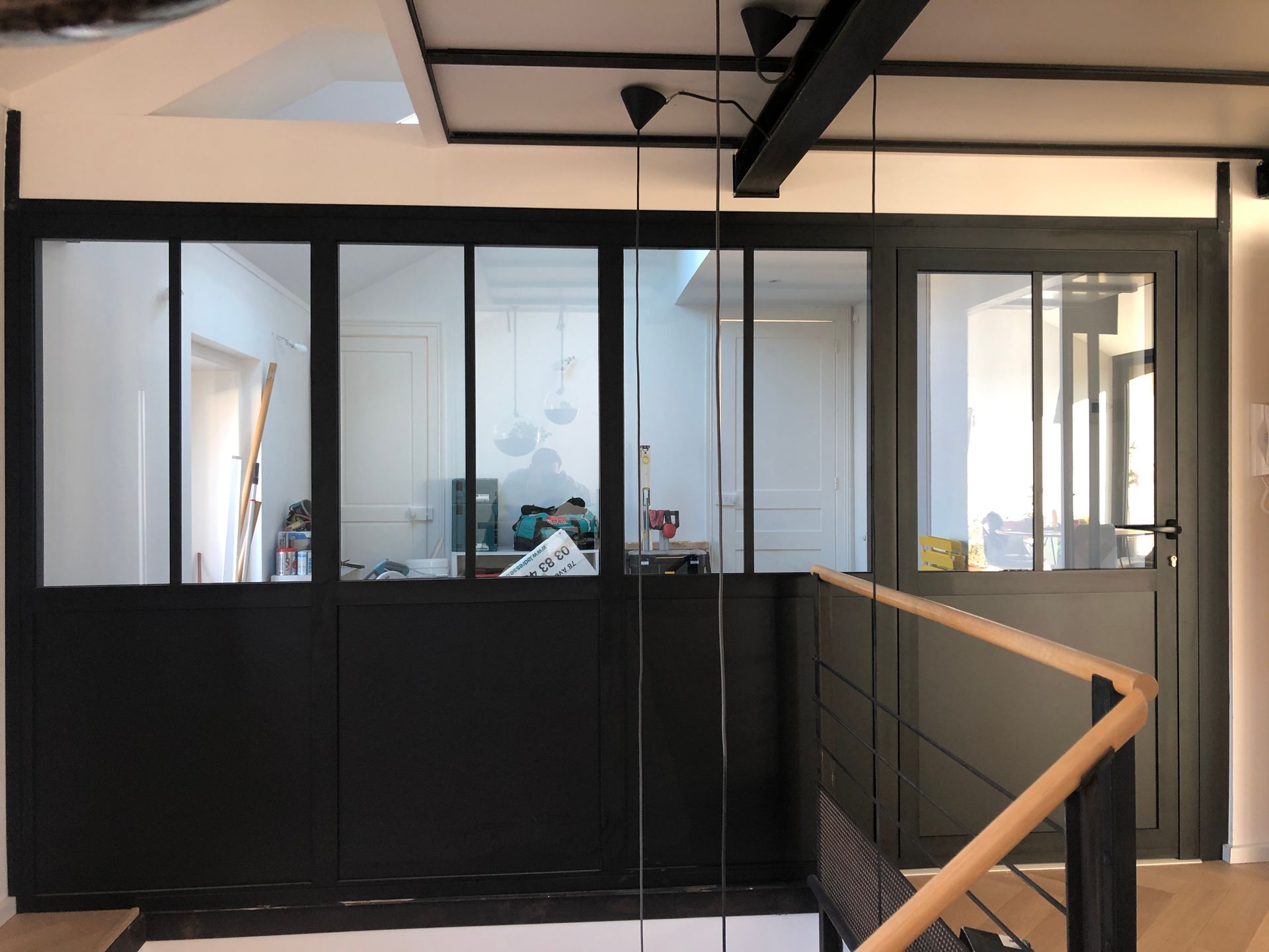 Porte-fenêtre ouverte donnant sur un balcon avec une échelle à l'intérieur. Vue extérieure avec stores baissés.