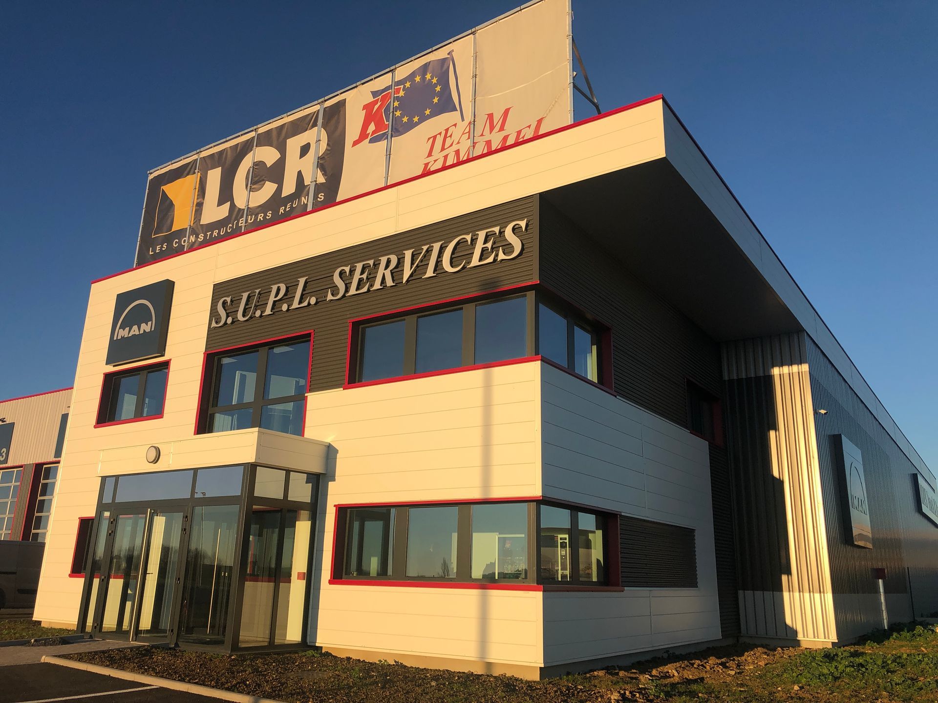 Façade avec porte vitrée fermée, boîte aux lettres et reflet de la rue.