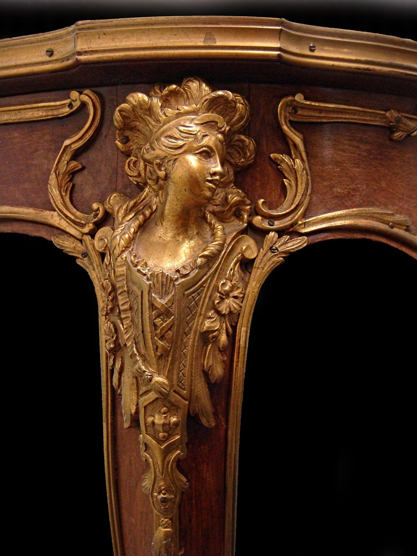 Monture en bronze doré ornée d'un buste féminin, sertie sur un meuble ancien de style français en bois sombre.
