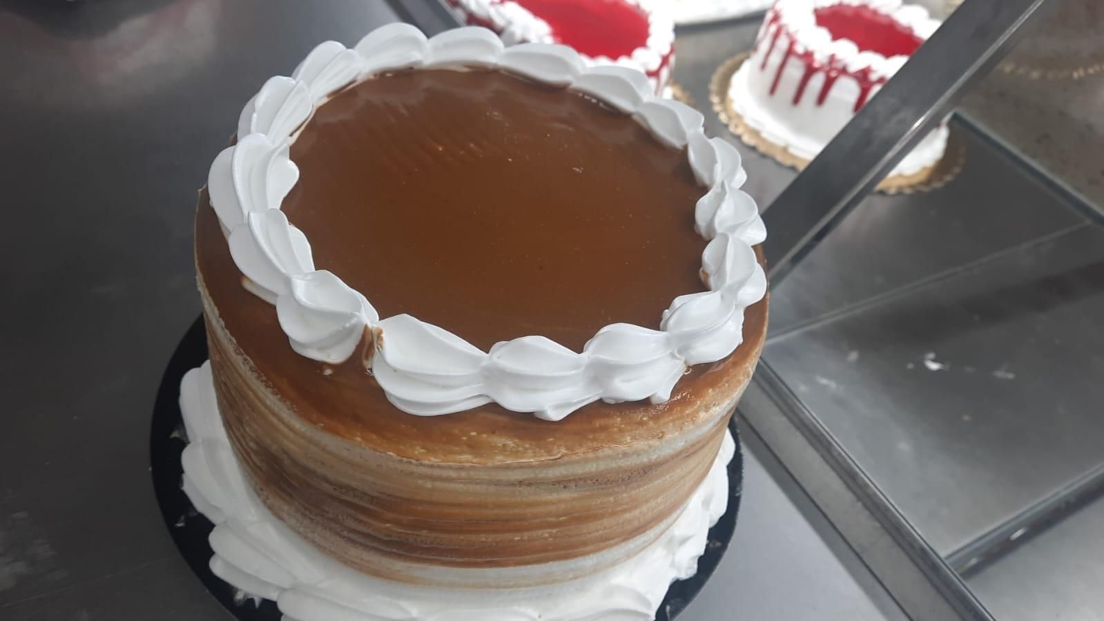 Pastel de caramelo con borde de glaseado blanco. Varias capas de pastel visibles. Dentro de una pastelería.