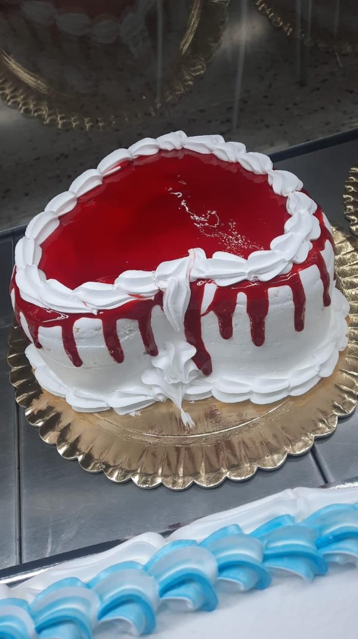 Pastel en forma de corazón con glaseado blanco, glaseado rojo y glaseado goteante.