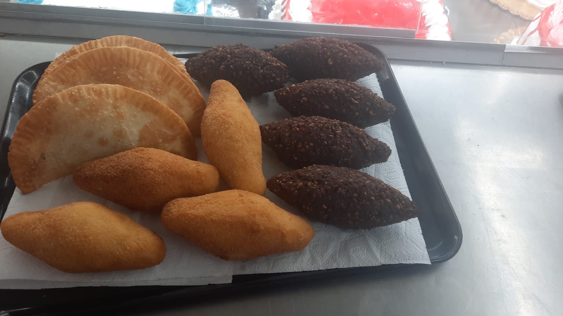 Tres panecillos dorados en un plato con hojas verdes y ramitas de perejil. Cuencos de condimentos al fondo.