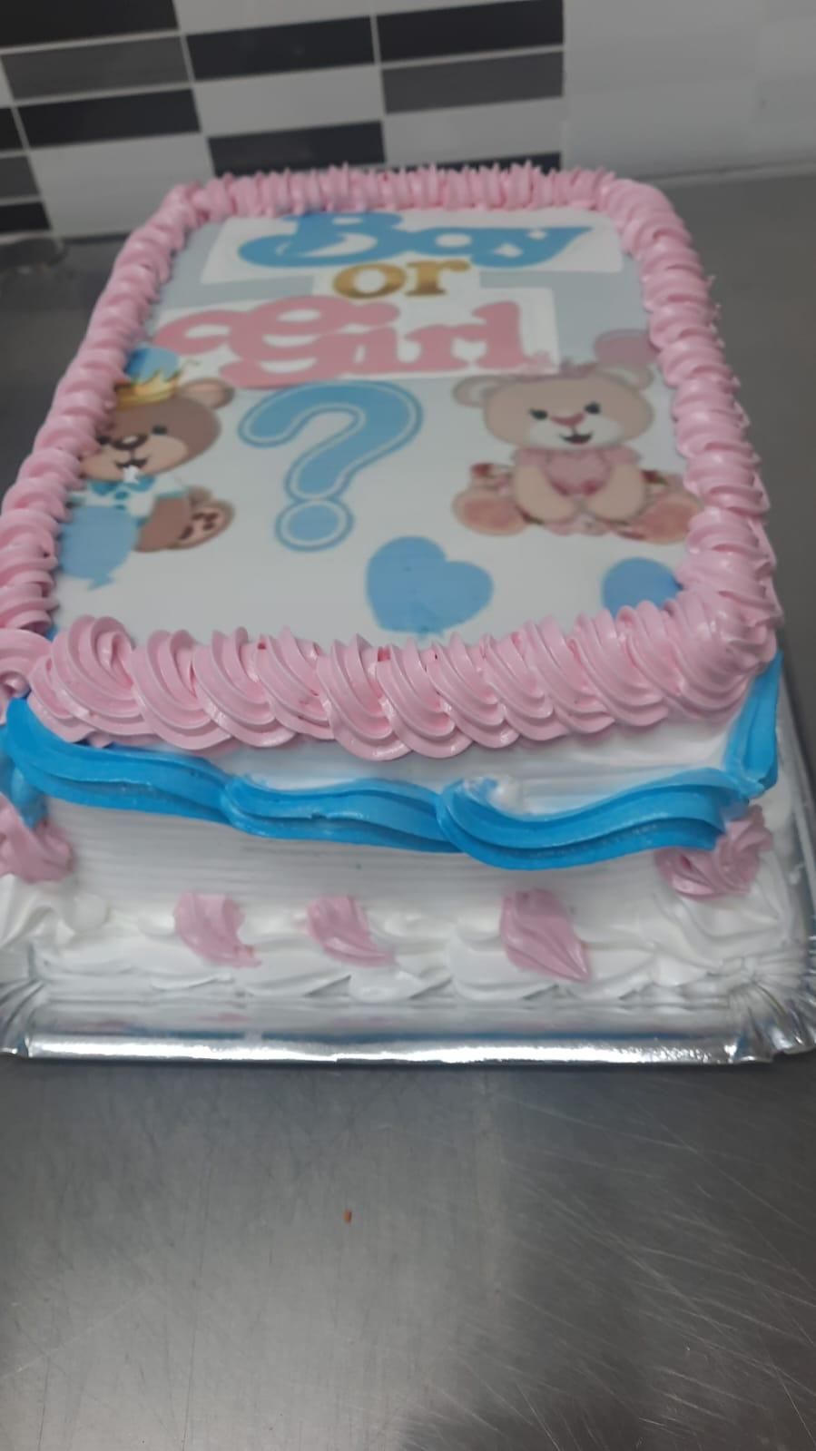 Pastel de revelación de género, glaseado rosa y azul, con decoraciones de ositos y signos de interrogación.