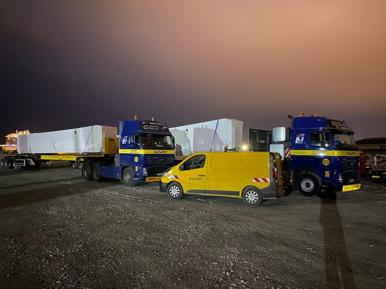 Voiture pilote garée près de camions de transport