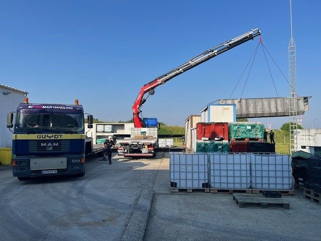 Plusieurs camions PromarHandling sur un chantier avec un bras qui soulève une benne