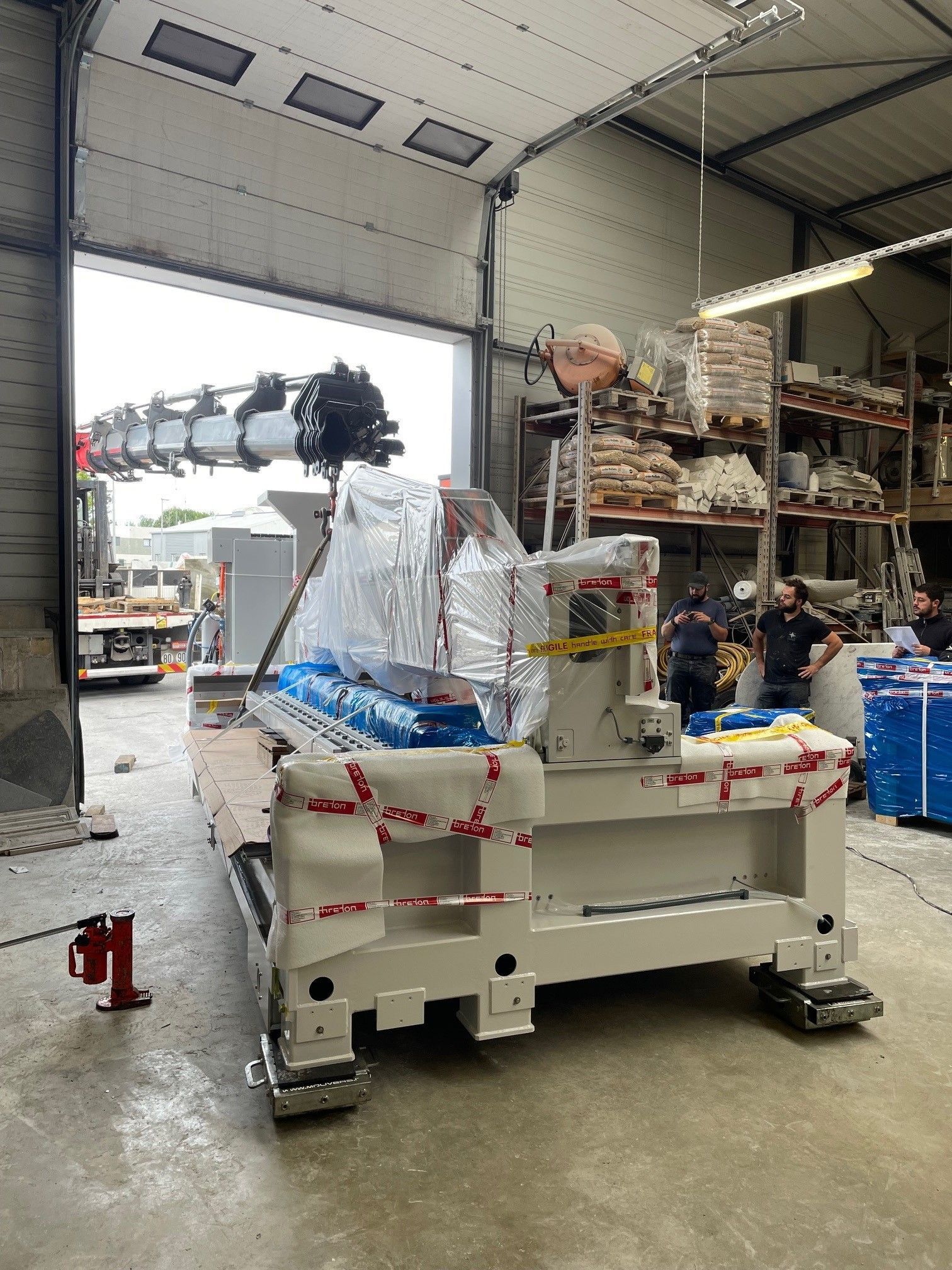 Bras de grue qui dépose une remorque blanche dans un entrepot