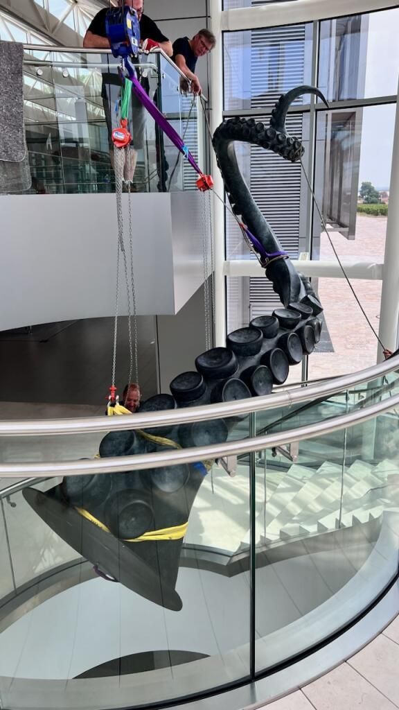 Statue de tentacule soulevée dans le vide pour son installation dans un bâtiment