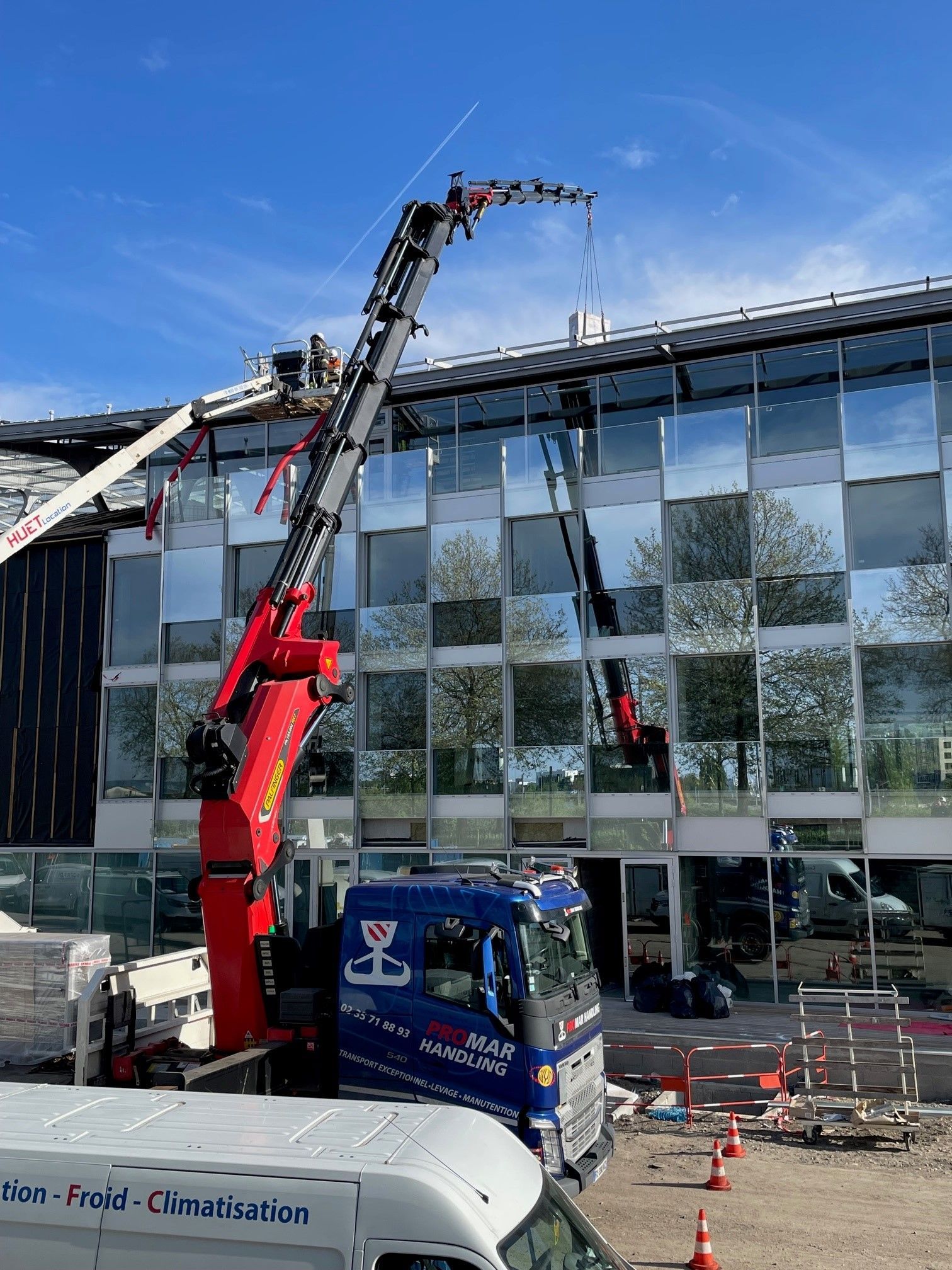 Bras de grue rouge déposant quelque chose au sommet d'un immeuble