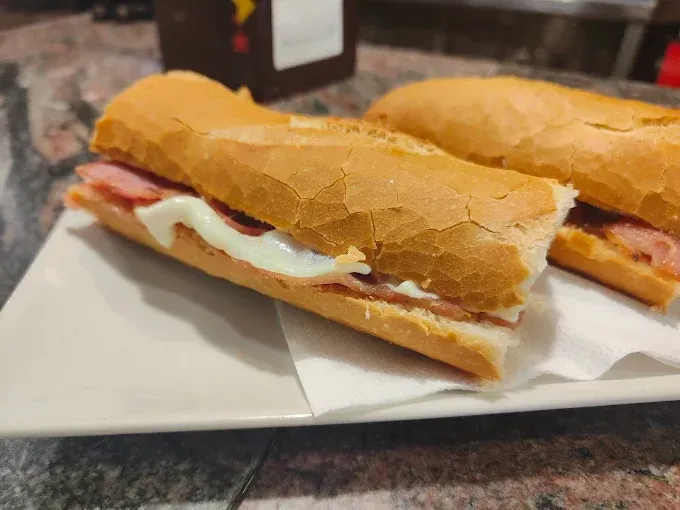 Dos sándwiches con jamón y salsa cremosa en un plato blanco.