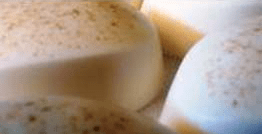 Visão aproximada de objetos redondos, esbranquiçados, com pintas marrons.