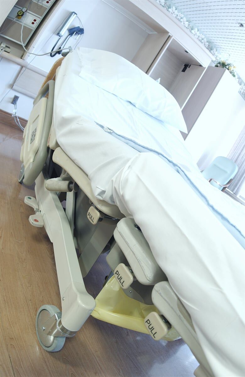 Cadeira odontológica revestida de branco, com apoio para as pernas e painéis de controle visíveis. 