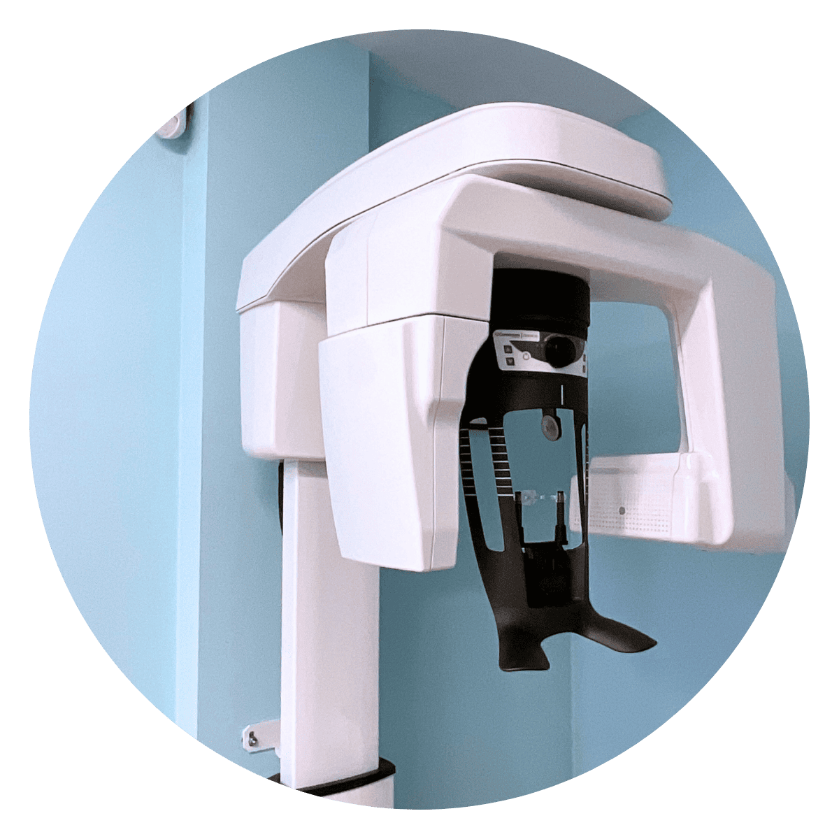Máquina de rayos X panorámicos dentales, blanca y negra, montada en una pared de color azul claro.