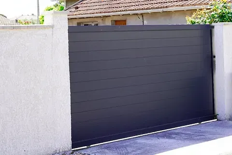 Una puerta corrediza negra está al lado de una pared blanca.