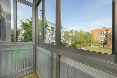 Un balcón con muchas ventanas y vista a una ciudad.