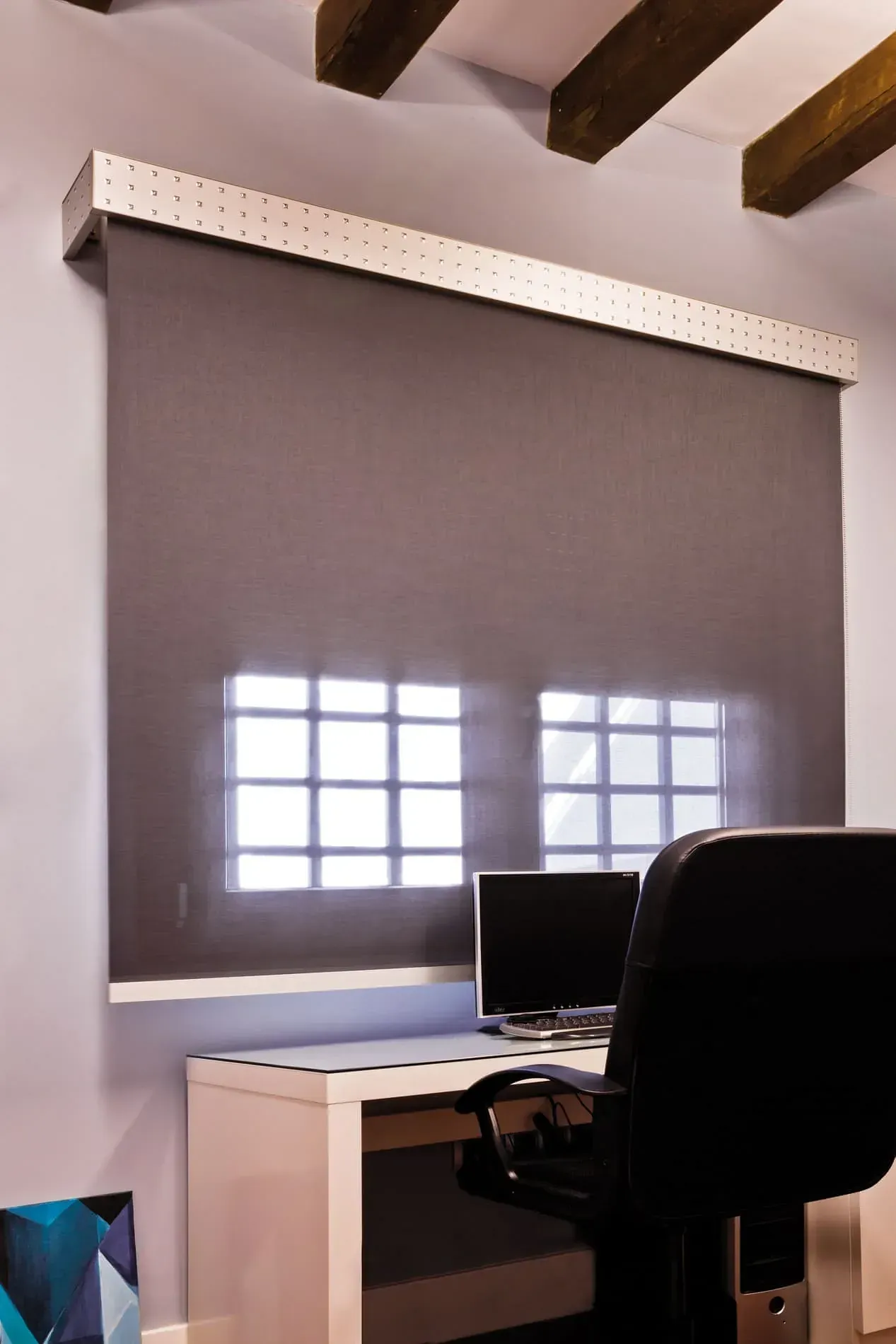 Una silla negra se encuentra frente a un escritorio con una computadora encima.