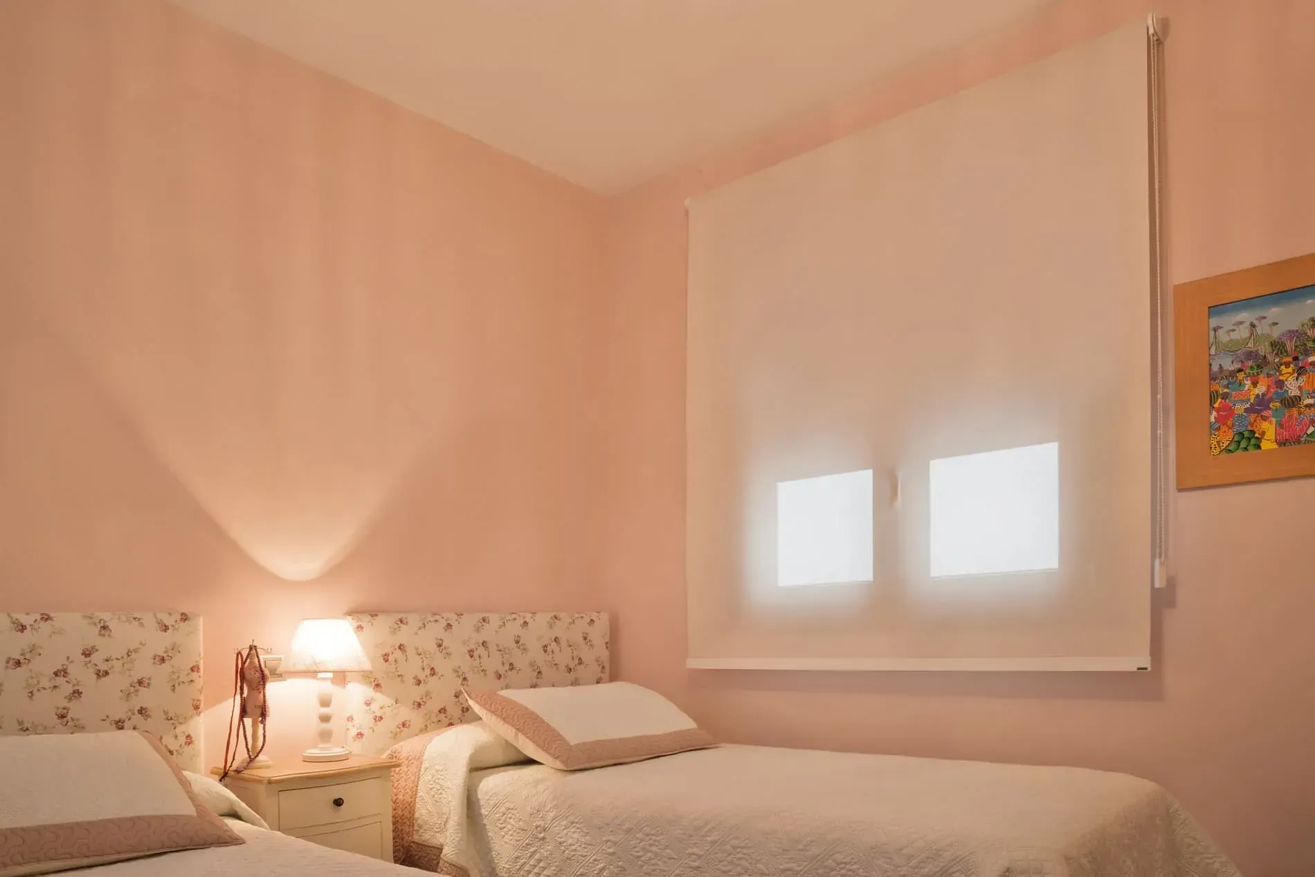 Un dormitorio con dos camas, una lámpara y un cuadro en la pared.