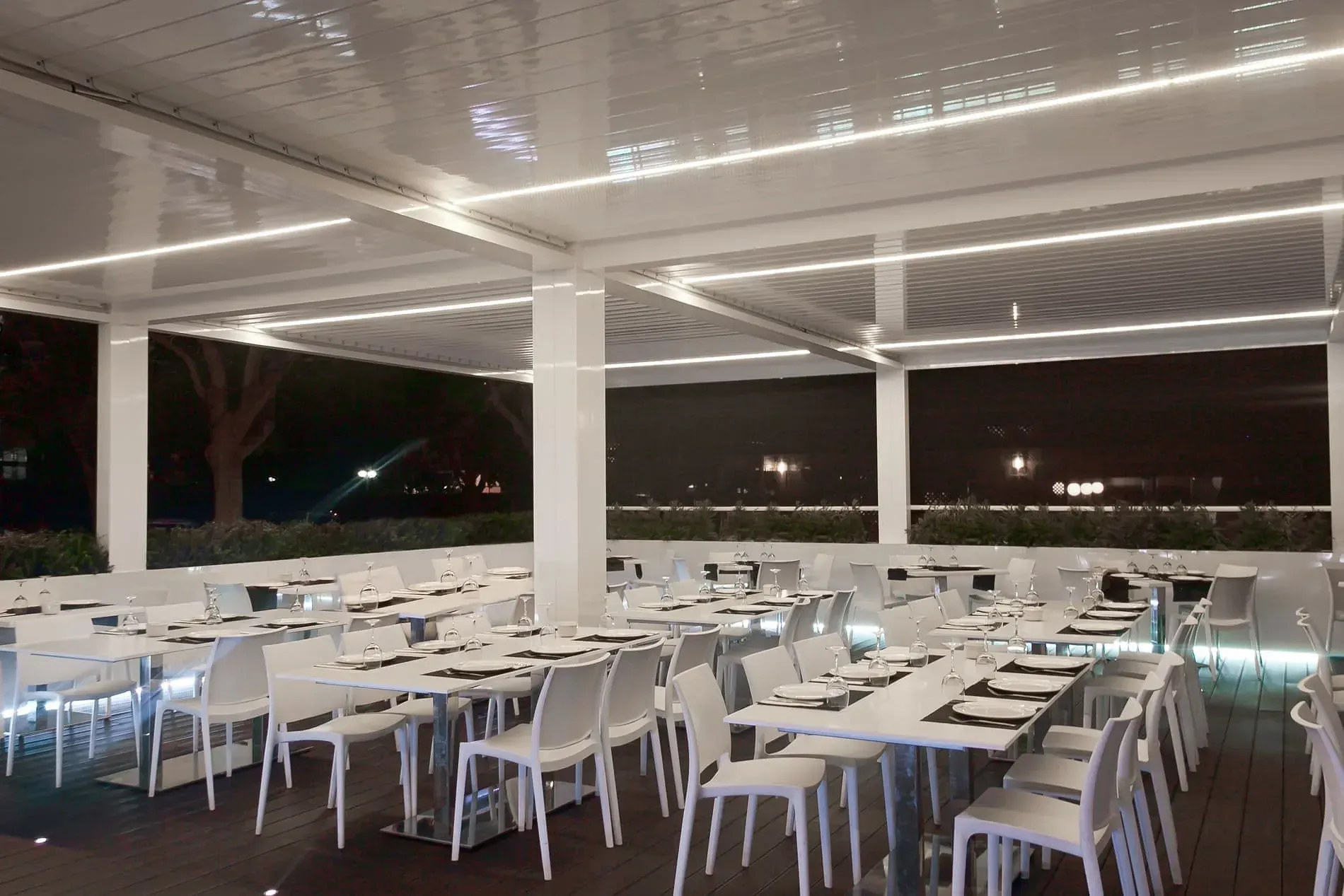 Un restaurante lleno de mesas y sillas por la noche.