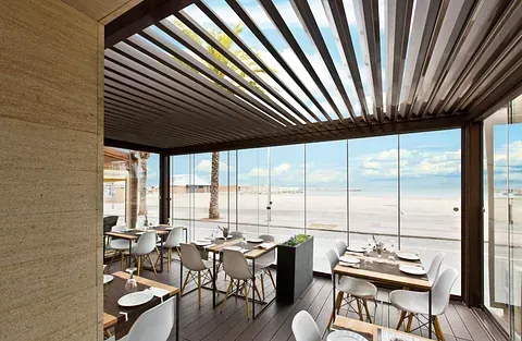 Un restaurante con mesas y sillas y vista al mar.