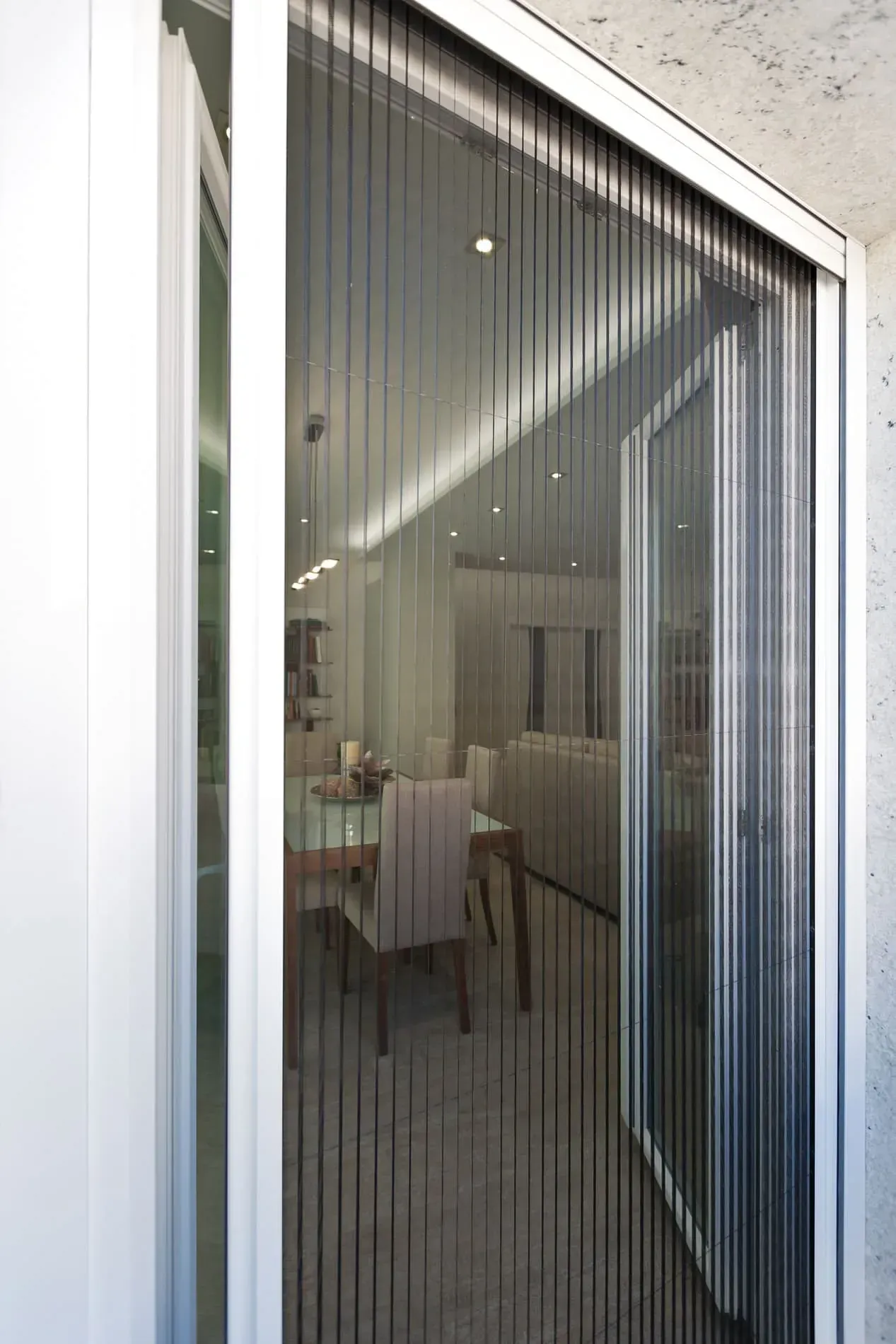 Un comedor con una mesa y sillas detrás de una puerta mosquitera.