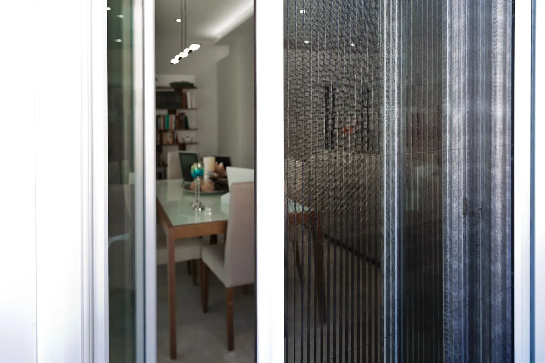 Una puerta corrediza de vidrio que conduce a un comedor con mesa y sillas.